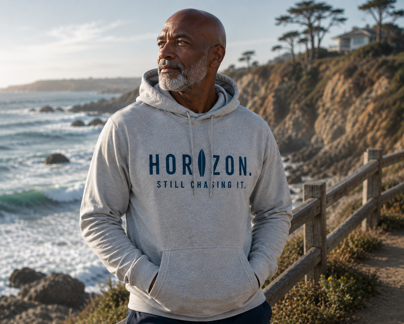 Man wearing the Horizon Still Chasing It hoodie on a coastal overlook