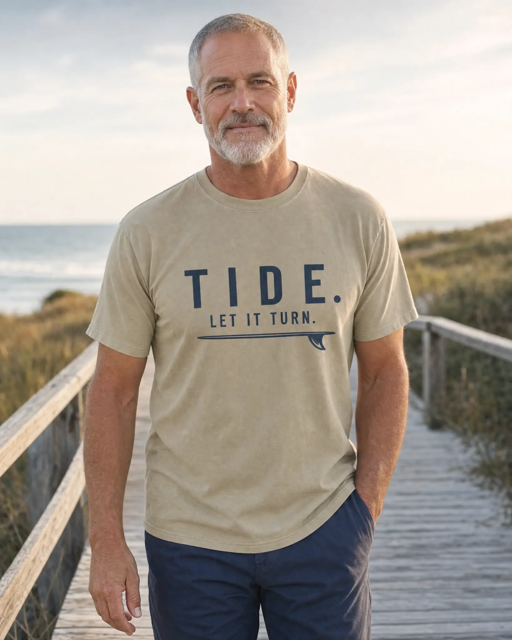 Man wearing the Tide Let It Turn T-shirt on a coastal boardwalk